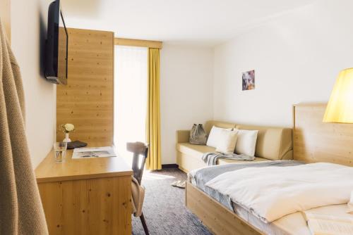 Habitación de hotel con cama y sofá en Posthotel, en Lutago
