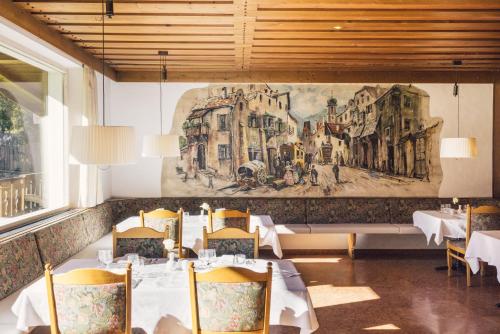 a restaurant with tables and chairs and a painting on the wall at Posthotel in Lutago