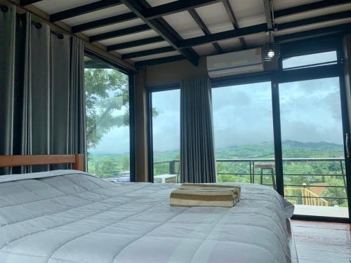 um quarto com uma cama grande e janelas grandes em เขาค้อ กุหลาบแดง รีสอร์ท em Khao Kho