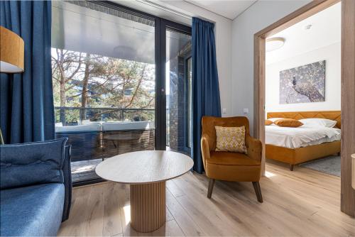 ein Zimmer mit einem Bett, einem Tisch und einem Stuhl in der Unterkunft Vanagupes Park Apartments, By Cohost in Palanga