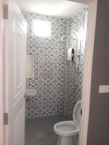 a bathroom with a toilet and a tile wall at sweet home phangan n5 in Srithanu