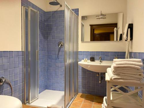 y baño de azulejos azules con ducha y lavamanos. en B&B Tenuta Montegrande, en San Salvatore Monferrato