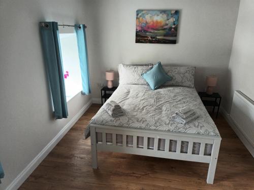 a bedroom with a white bed with blue pillows and a window at Fabulous Belmullet Townhouse in Belmullet