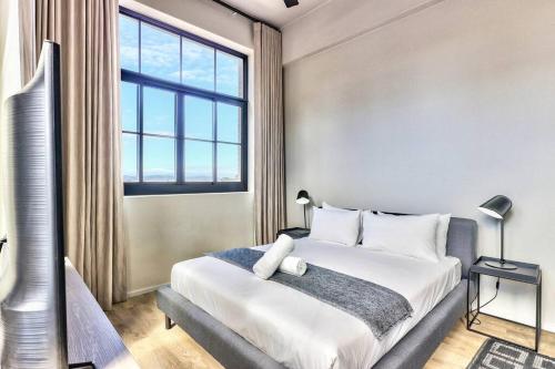 ein Schlafzimmer mit einem großen Bett und einem großen Fenster in der Unterkunft Upmarket Urban Apartment in the East City w/ Vi in Kapstadt