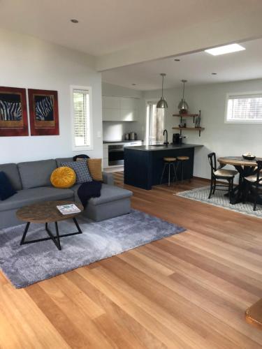 a living room and kitchen with a couch and a table at Torbay Tree Tops in Auckland