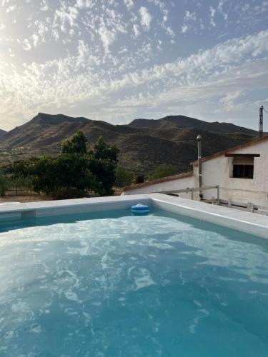 ein blauer Pool mit Bergen im Hintergrund in der Unterkunft Luby Cortijo Las Eras in Lubrín