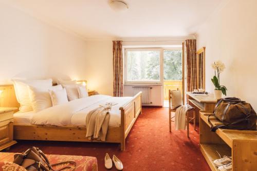 1 dormitorio con cama, escritorio y ventana en Parkhotel Schachen en San Giovanni in Val Aurina