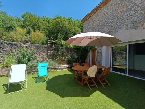 a table and chairs with an umbrella on a lawn at Maison sur le Lot in Saint-Vincent-Rive-dʼOlt
