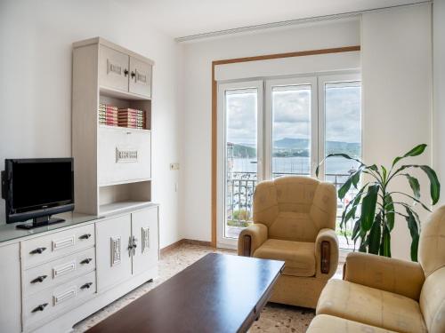 salon z telewizorem, dwoma krzesłami i stołem w obiekcie PARAISO RIAS BAIXAS II Combarro w mieście Combarro