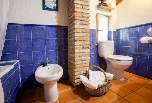 a blue tiled bathroom with a toilet and a sink at Hotel Rural Valleoscuru in Tresgrandas