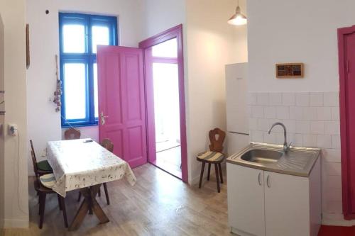 une cuisine avec une porte rose, une table et un évier dans l'établissement Josephine Central Villa & Garden, à Cluj-Napoca