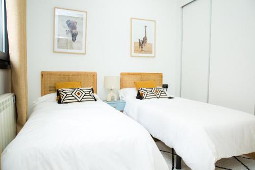 two beds in a room with white walls at Luminoso Apartamento NUEZ - Zonas verdes, Wifi, Aparcamiento gratuito in Valladolid