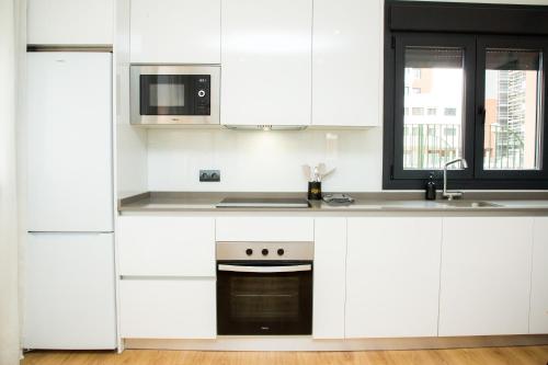 a white kitchen with white cabinets and a microwave at Luminoso Apartamento NUEZ - Zonas verdes, Wifi, Aparcamiento gratuito in Valladolid