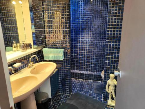 La salle de bains est pourvue d'un lavabo et d'une douche avec du carrelage bleu. dans l'établissement Penthouse champs elysées above 5 stars hotel berri champs elysées, à Paris