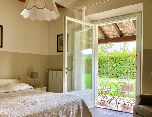 a bedroom with a bed and a sliding glass door at Relais Le Fornacelle in Castagneto Carducci