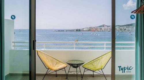 a balcony with two chairs and a view of the ocean at Typic Marina Playa - Adults Only in San Antonio Bay