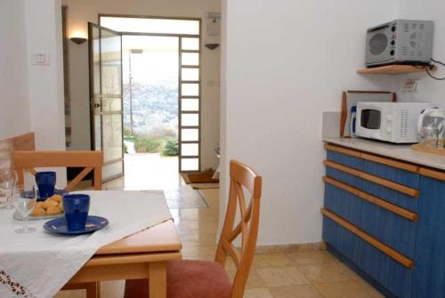 a kitchen with a dining table and a microwave at Keshet Eilon - Suites and Villas in Elon