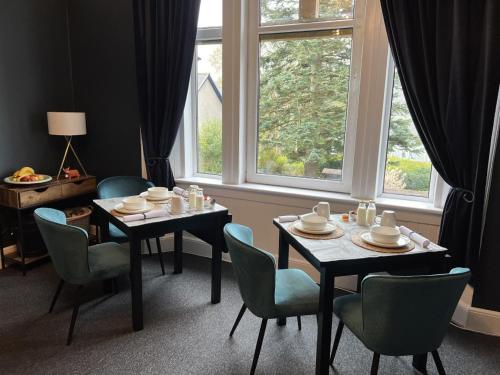 una sala da pranzo con due tavoli, sedie e una finestra di Ravenswood House B&B a Fort William