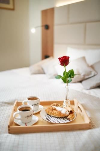 a tray with two cups of coffee and a rose on a bed at Hotel Wellness & Spa Nowy Dwór in Rzeszów