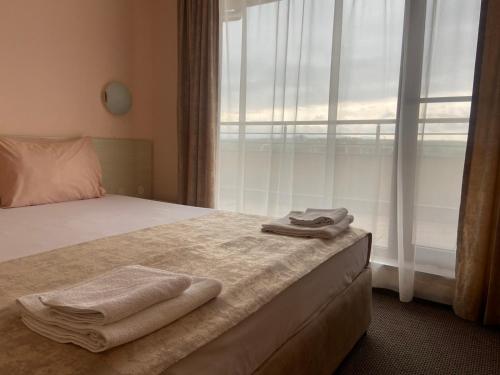 a bedroom with a bed with two towels on it at Aparthotel Hotel Prestige City II in Primorsko