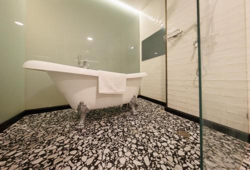 a bathroom with a tub and a glass shower at Garden Hotel Boutique & Events in Haifa