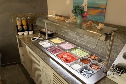 a kitchen counter with several trays of food at Cristiani Hotel Sozopol in Sozopol