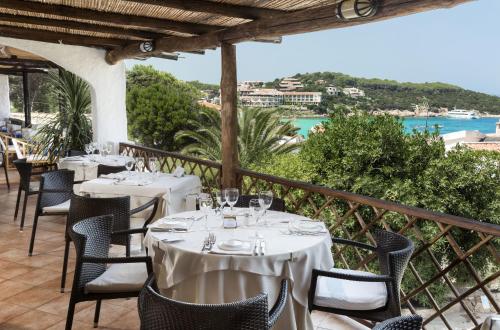 a restaurant with tables and chairs with a view of the ocean at Hotel La Bisaccia in Baja Sardinia
