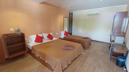 a hotel room with two beds with red pillows at Straits Settlement Inn in Melaka