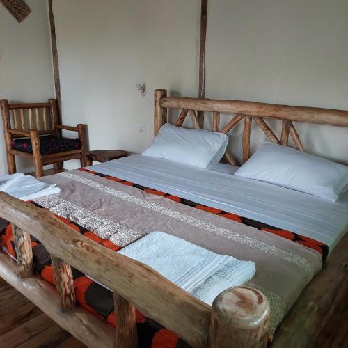 a wooden bed with two pillows and towels on it at Songbird Safari Lodge & Campsite in Katunguru