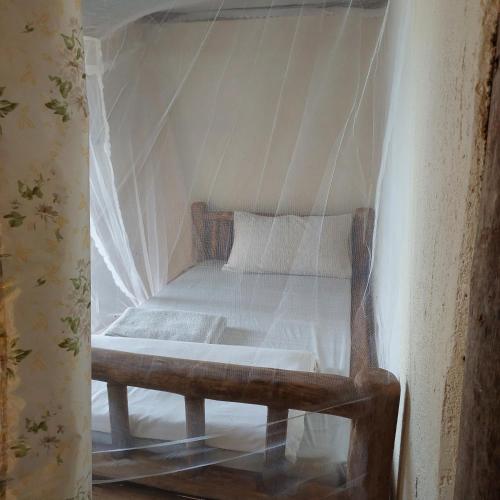 a bed with a net in a room at Songbird Safari Lodge & Campsite in Katunguru
