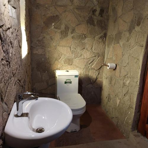 a stone bathroom with a sink and a toilet at Songbird Safari Lodge & Campsite in Katunguru