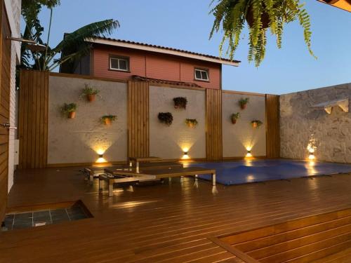 un patio avec bancs et lumières devant un mur dans l'établissement Casa com piscina em frente à Praia do Santinho, à Florianópolis