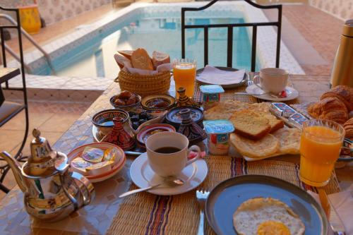 a breakfast table with breakfast foods and drinks and a pool at Riad Parfums de OUARZAZATE in Ouarzazate