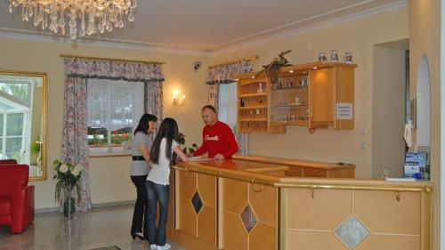a man and a woman standing at a kitchen counter at Gästehaus Am Ludwigsberg in Bad Koetzting