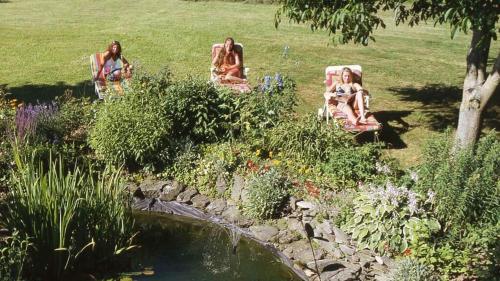 two women sitting in chairs in a garden with a pond at Gästehaus Am Ludwigsberg in Bad Koetzting