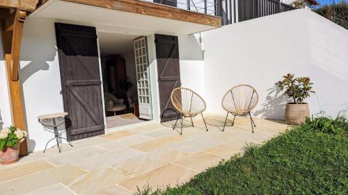 2 chaises assises sur une terrasse à côté d'un bâtiment dans l'établissement Maison Caiada, à Urrugne