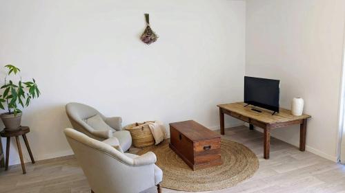 sala de estar con 2 sillas, TV y mesa en Maison Caiada en Urrugne