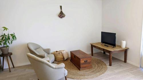 a living room with two chairs and a tv and a table at Maison Caiada in Urrugne