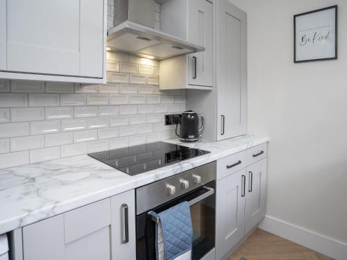 a kitchen with white cabinets and a stove top oven at The Views Townhouse in Newcastle