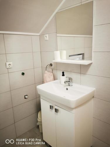a white bathroom with a sink and a mirror at Vila Julija - Apartment & rooms in Otočac