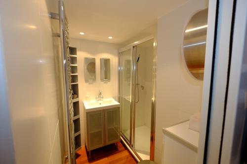 a white bathroom with a shower and a sink at Le Balcon de Valberg in Valberg