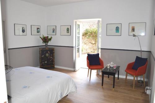 a bedroom with a bed and two chairs and a table at La Roche Cantin in Cherveux