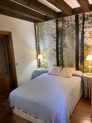 1 dormitorio con 1 cama grande con árboles en la pared en La Hoja de Roble en Puebla de Sanabria