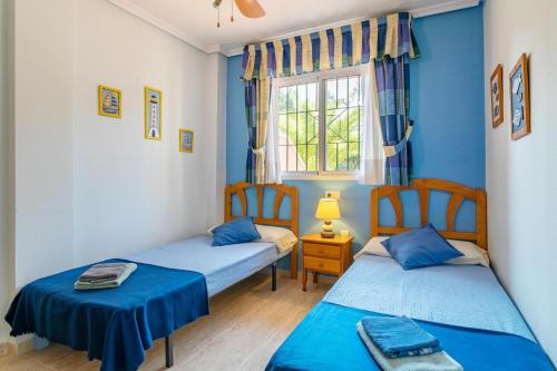 two beds in a room with blue walls and a window at Apartment near the beach in Gran Alacant