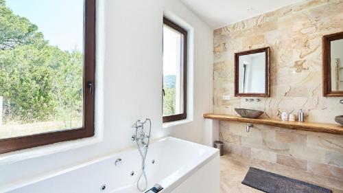 a bathroom with a tub and a stone wall at Hesperia - San Jose in Sant Josep de sa Talaia