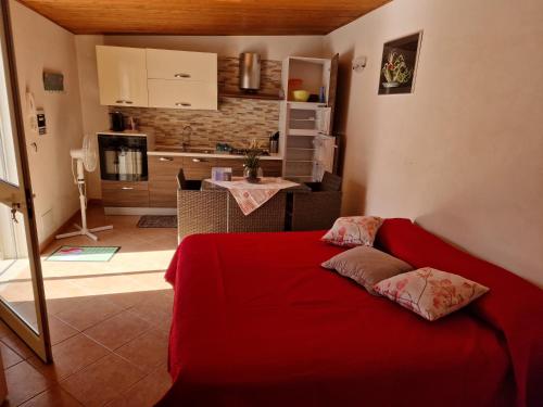 ein rotes Bett in einem Zimmer mit einer Küche in der Unterkunft Villa Panorama sulle Egadi in Parrinello 