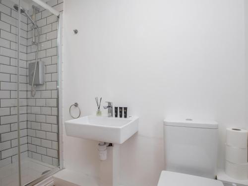 a white bathroom with a sink and a toilet at Pass the Keys Brambles Spacious Home Sleeps 8 Legoland Windsor in 5mins in Windsor