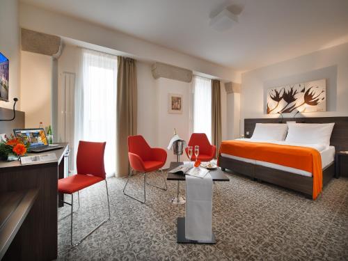 a hotel room with a bed and red chairs at EA Business Hotel Jihlava in Jihlava