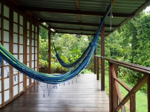 a hammock on the porch of a house at Hotel Finca Maresia in Drake