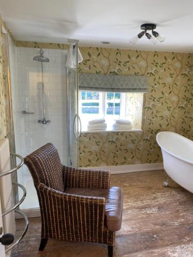 uma casa de banho com uma cadeira, uma banheira e uma janela em The Seagrave Arms em Weston Subedge